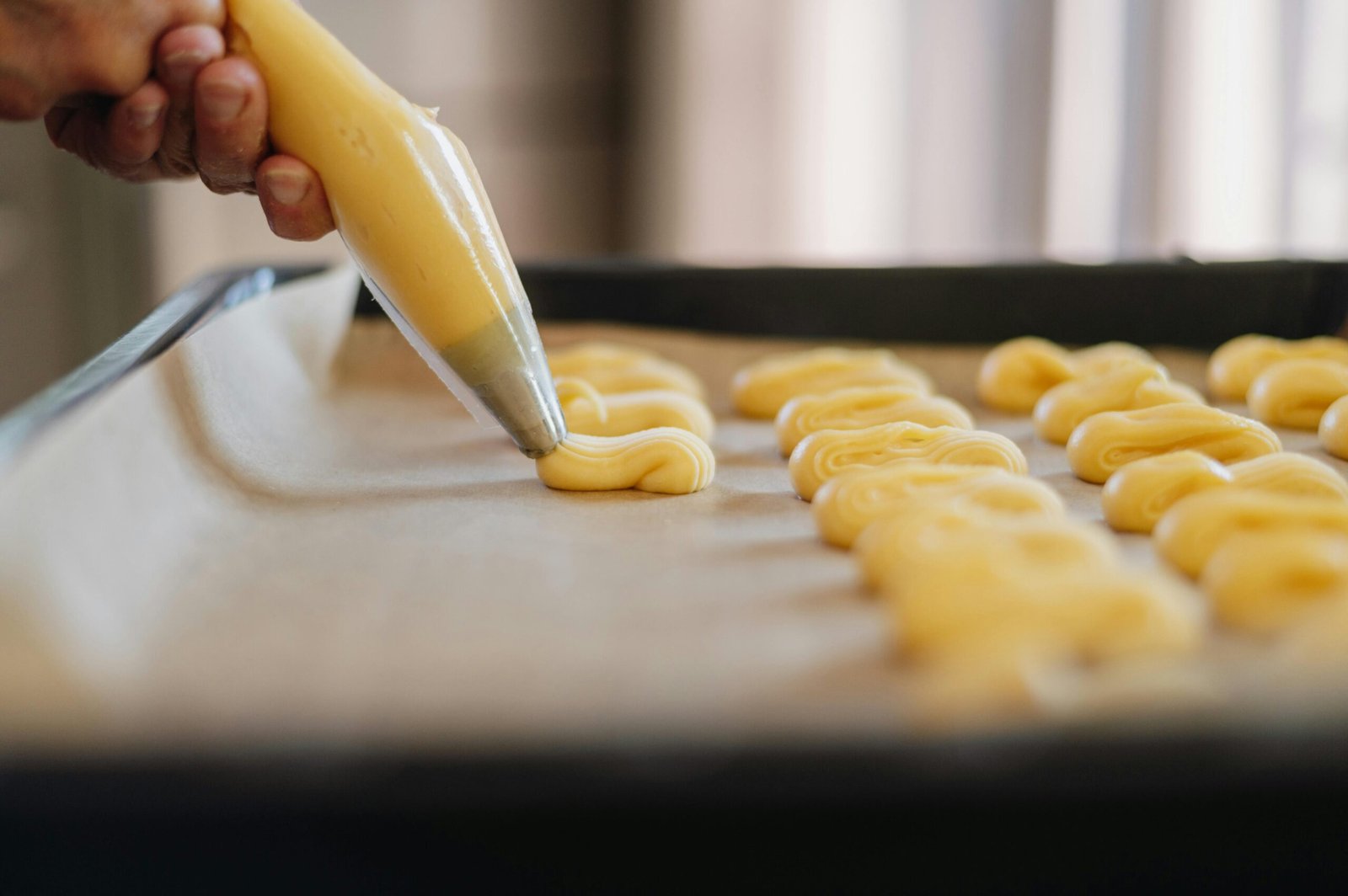 A close-up shot of dough being piped onto parchment paper, highlighting the art of baking.